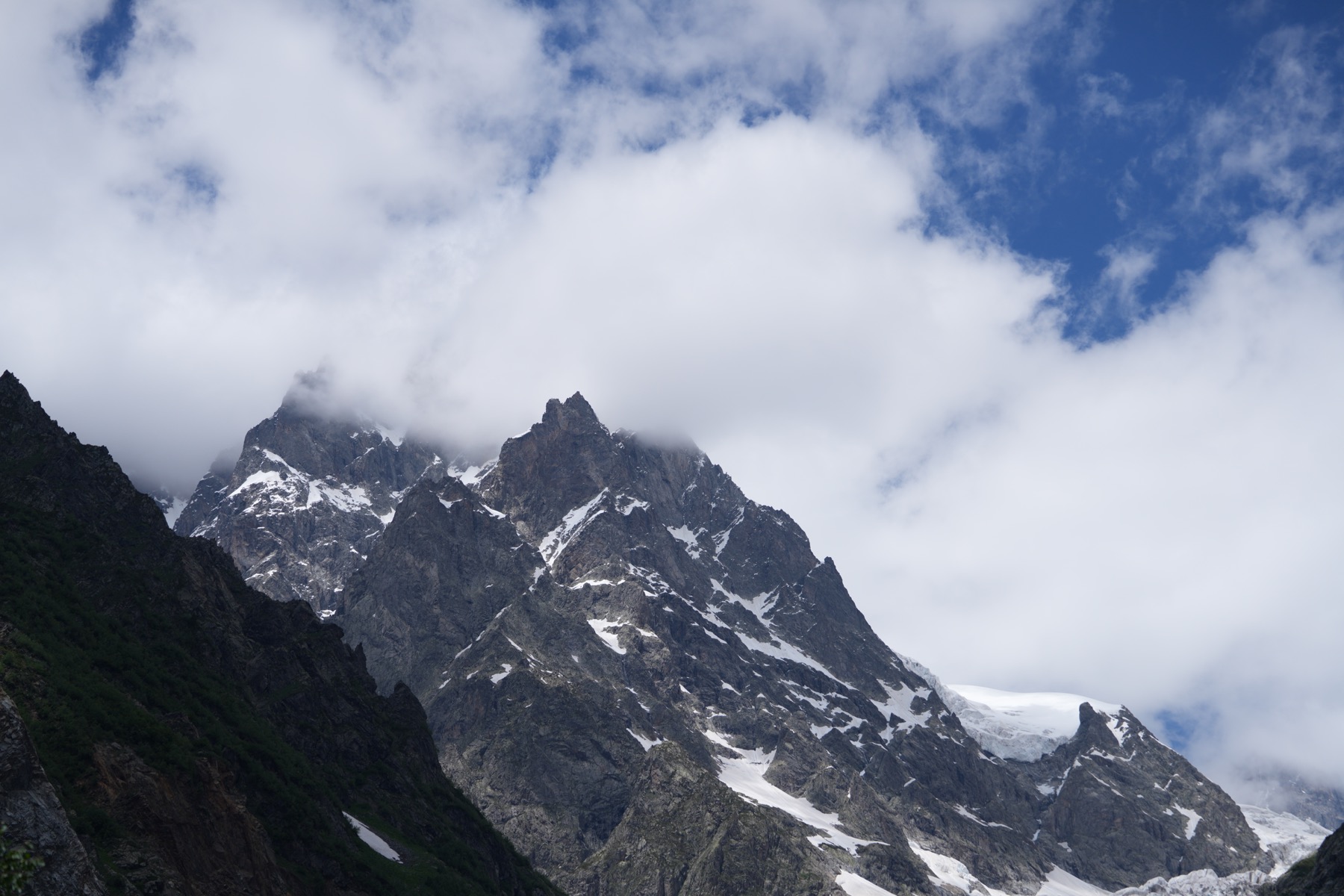 Jagged snow-covered Caucasus peaks rising into low clouds