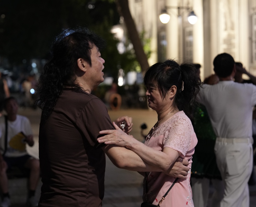 Two people dancing beside the Haihe River in Tianjin at night